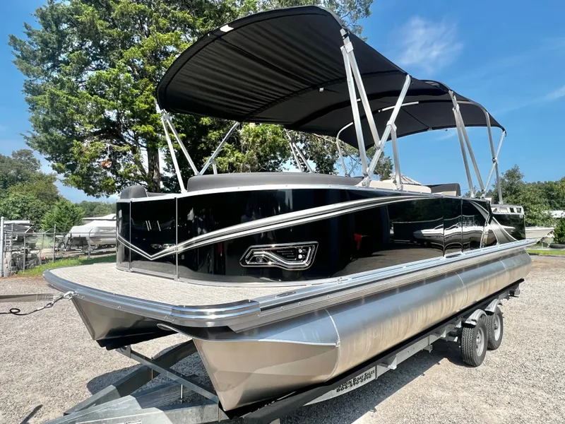 Slide: The Image of A sleek pontoon boat with a black canopy and silver hull sits on a trailer. - 7
