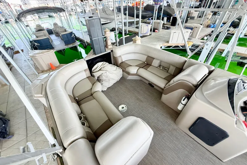 Slide: The Image of 2017 Bentley Pontoons 223 Elite Cruise interior with plush seating at a marina. - 19