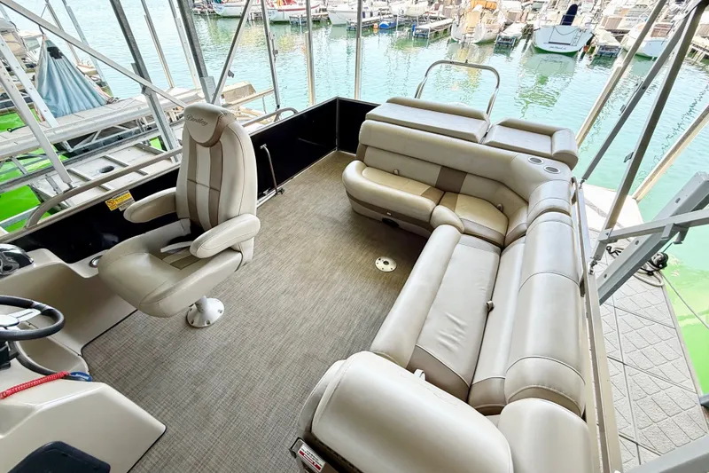 Slide: The Image of 2017 Bentley Pontoons 223 Elite Cruise interior with plush seating and helm, docked at marina. - 21