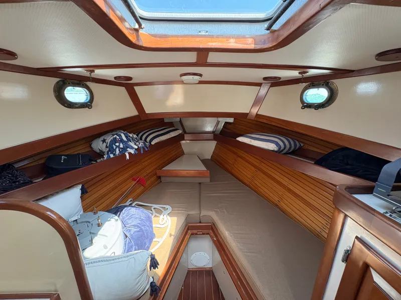 Slide: The Image of The interior of a 1988 Jarvis Newman 32 features a cozy cabin with wood paneling and portholes. - 22