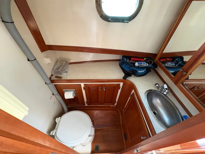 Slide: The Image of The image shows a boat bathroom with wood paneling, a sink, and a toilet. - 23