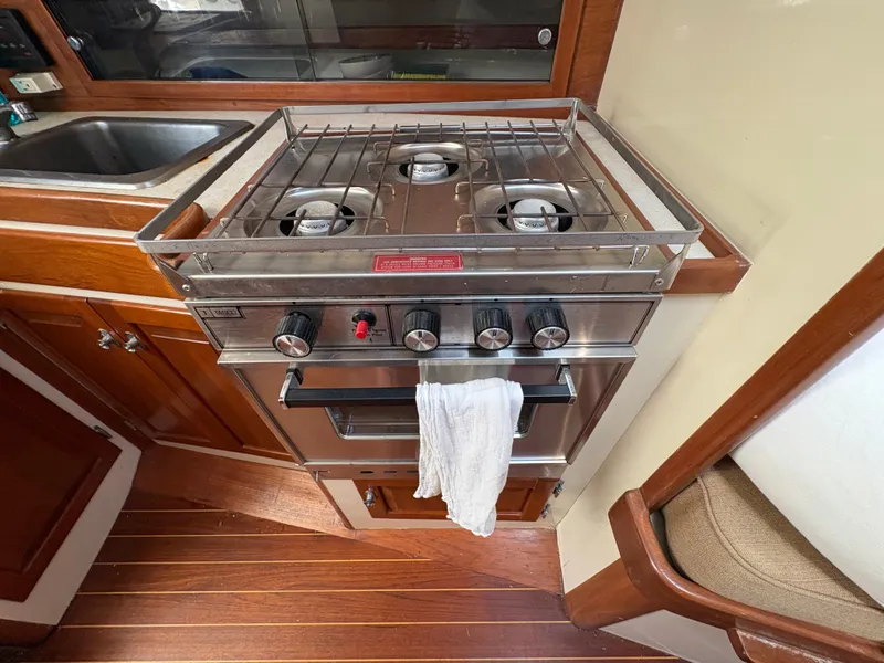 Slide: The Image of The galley of a boat with a stainless steel stove and a sink beside it. - 21
