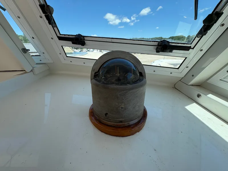 Slide: The Image of A compass on a boat with windows and blue sky in the background. - 16