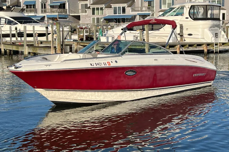 The Image of 2006 Monterey 248LS Montura Bowrider in marina, red and white design, calm water reflection. - 2
