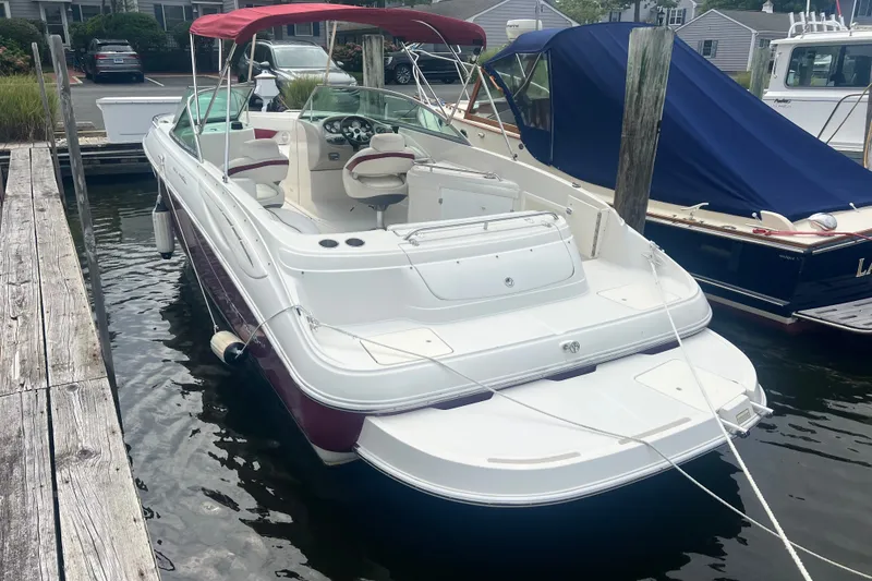 Slide: The Image of 2006 Monterey 248LS Montura Bowrider docked, featuring red canopy and spacious seating. - 6