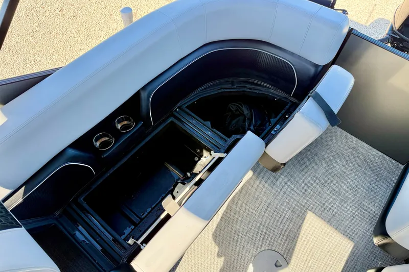 Slide: The Image of Interior seating and storage of 2027 Vanderbilt 23QS boat, featuring cup holders and carpeted flooring. - 31