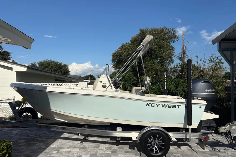 The Image of 2027 Key West 179 FS boat on trailer, parked outdoors under clear blue sky. - 0