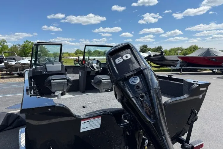 Slide: The Image of 2026 Crestliner 1650 Kodiak WT boat with 60 HP motor, parked outdoors under a blue sky. - 15