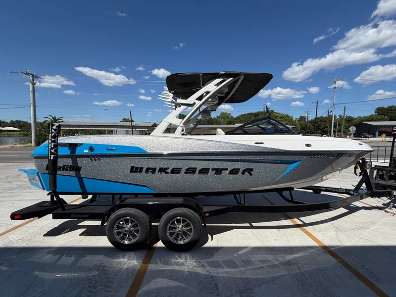 Slide: The Image of A silver 2016 Malibu Wakesetter 23 LSV on a trailer under a blue sky. - 6