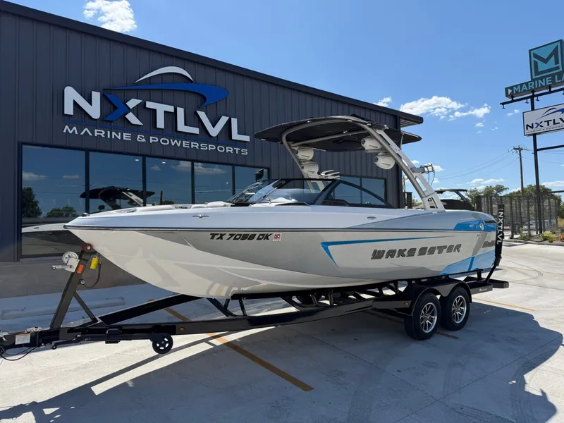 Slide: The Image of A white 2016 Malibu Wakesetter 23 LSV boat on a trailer in front of a building. - 2