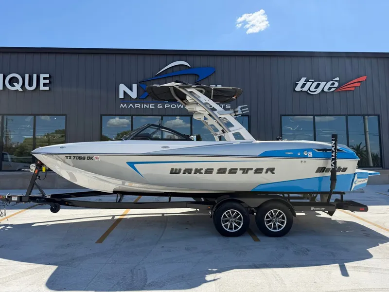 The Image of A 2016 Malibu Wakesetter 23 LSV on a trailer in front of a building. - 1