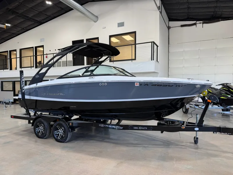 The Image of A 2022 Regal LS2 Surf boat on a trailer in a showroom setting. - 1