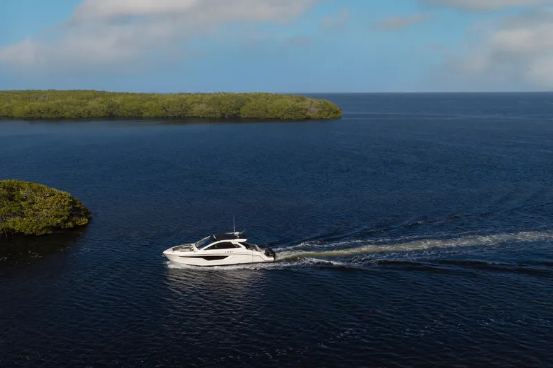 Slide: The Image of 2021 Cruisers Yachts 42 GLS OB cruising on a serene blue lake. - 34