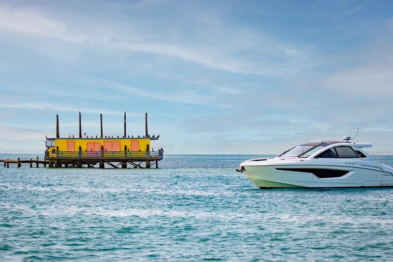 Slide: The Image of 2021 Cruisers Yachts 42 GLS OB near colorful dock on serene water. - 35