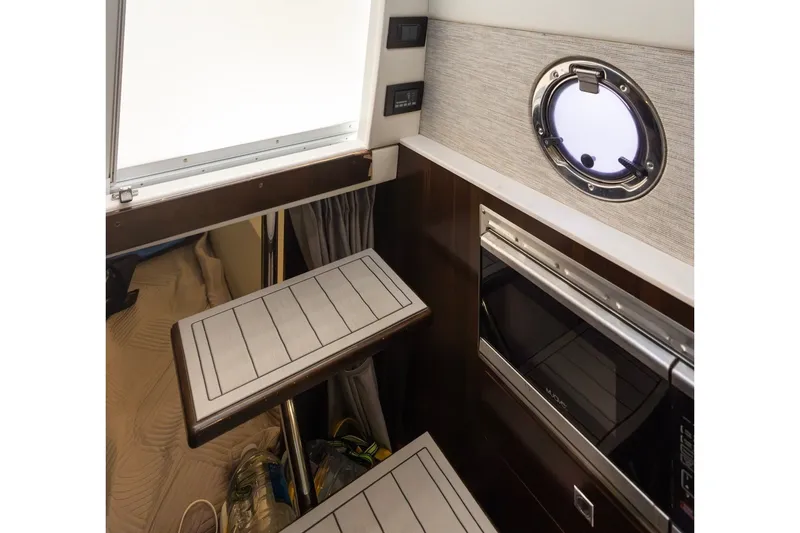 Slide: The Image of Interior of 2021 Cruisers Yachts 42 GLS OB, featuring modern kitchenette and porthole window. - 15