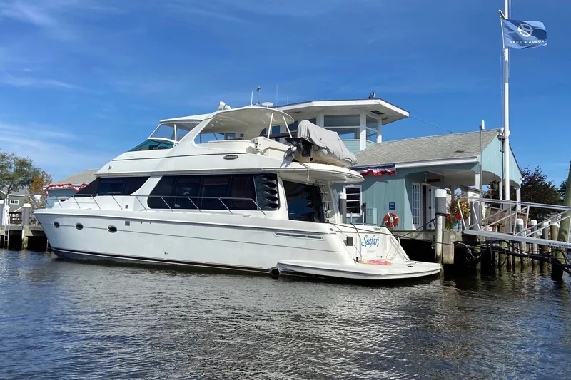 Slide: The Image of 2004 Carver 570 Voyager Pilothouse yacht docked at marina under clear blue sky. - 1