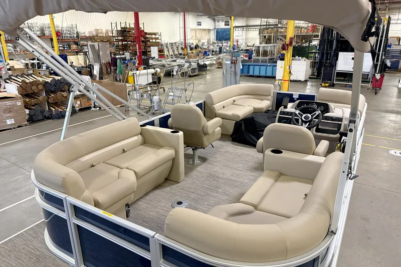 Slide: The Image of 2027 Godfrey EX 2086 SBX pontoon boat interior with beige seating in a factory setting. - 11
