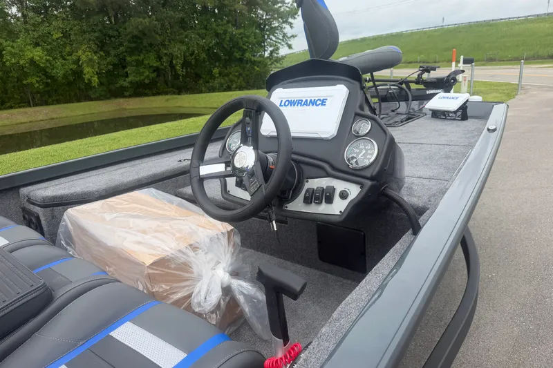 Slide: The Image of 2027 Ranger RT178 boat dashboard with Lowrance electronics and steering wheel, parked near greenery. - 8