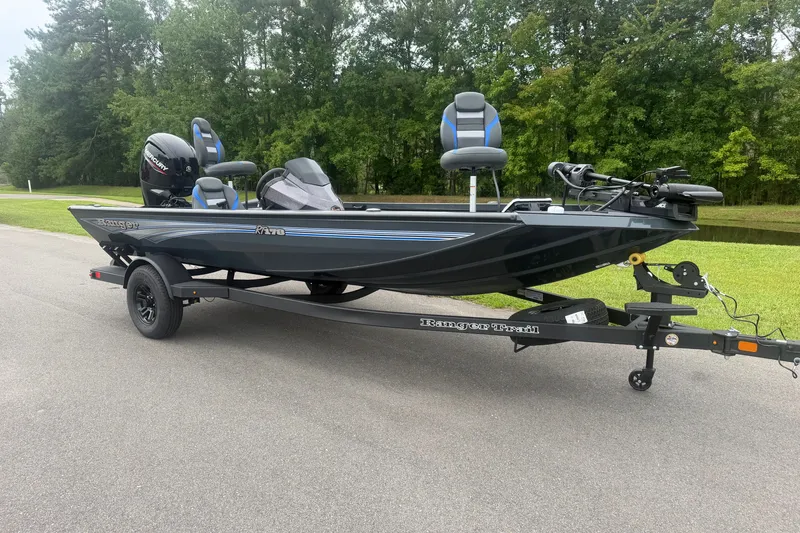 Slide: The Image of 2027 Ranger RT178 boat on trailer, parked on road with green trees in background. - 2