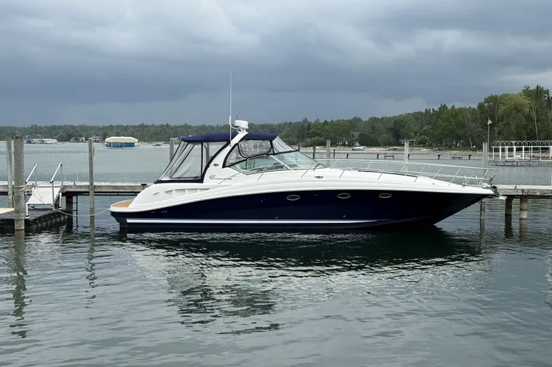 The Image of 2004 Sea Ray 420 Sundancer yacht docked on a calm lake under cloudy skies. - 0