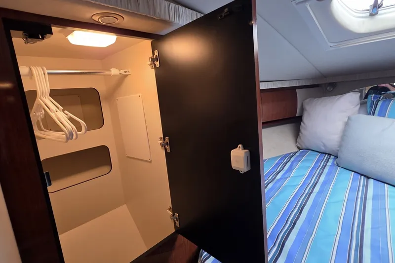 Slide: The Image of Interior of 2004 Sea Ray 420 Sundancer showing closet and bed with striped bedding. - 40