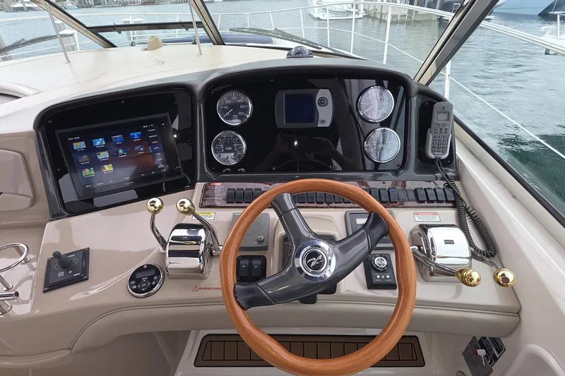 Slide: The Image of 2004 Sea Ray 420 Sundancer helm with wooden steering wheel and modern navigation controls. - 12