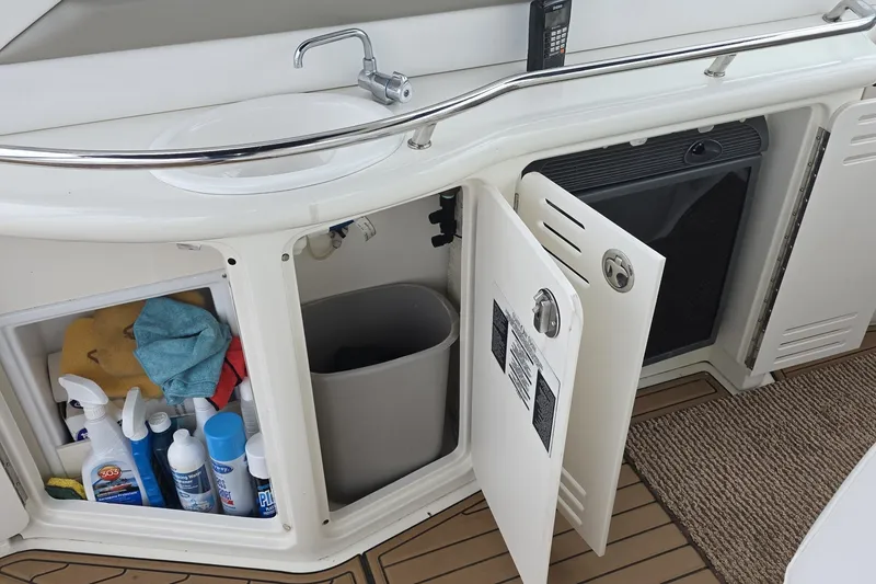 Slide: The Image of 2004 Sea Ray 420 Sundancer yacht interior with sink, storage, and cleaning supplies. - 18