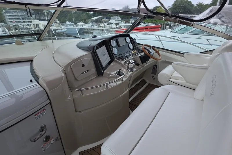 Slide: The Image of 2004 Sea Ray 420 Sundancer helm with modern controls and luxurious seating at a marina. - 10