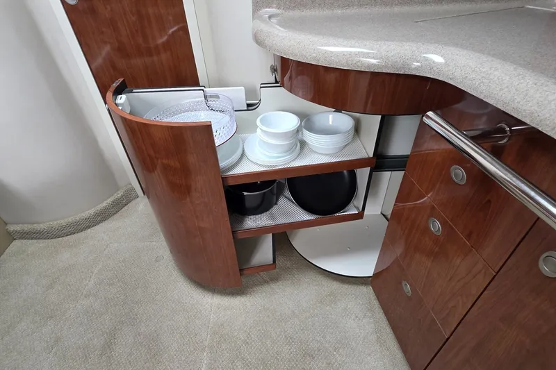 Slide: The Image of 2004 Sea Ray 420 Sundancer kitchen cabinet with open shelves displaying dishes and bowls. - 26
