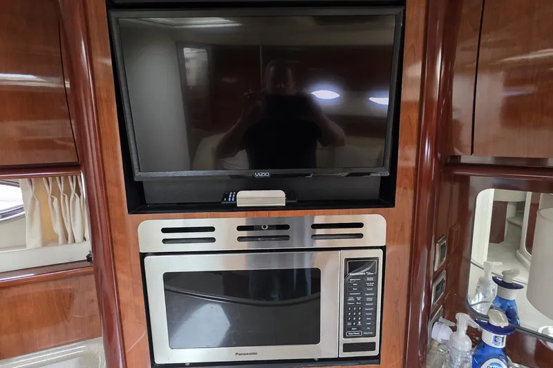 Slide: The Image of 2004 Sea Ray 420 Sundancer interior with TV and microwave in wooden cabinetry. - 28
