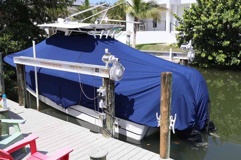 Slide: The Image of Covered 2009 Boston Whaler 280 Outrage boat docked, surrounded by lush greenery and a wooden deck. - 13