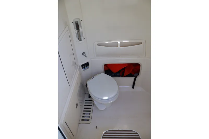 Slide: The Image of Interior of 2009 Boston Whaler 280 Outrage boat, featuring a compact marine toilet. - 10