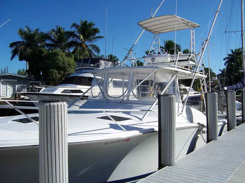 The Image of 1998 Luhrs Express Sportfish boat docked, surrounded by palm trees and clear blue sky. - 0