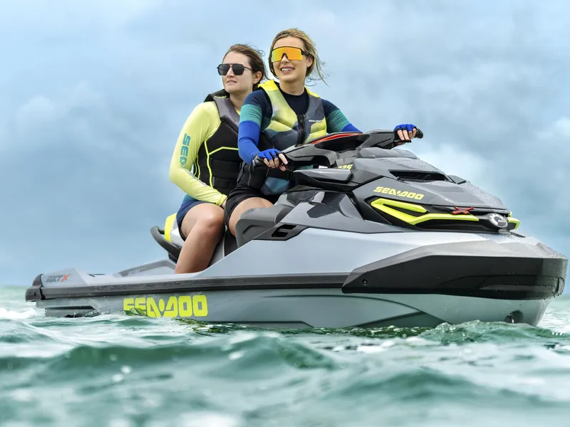 Slide: The Image of Two people ride a gray Sea-Doo jet ski on the water. - 42