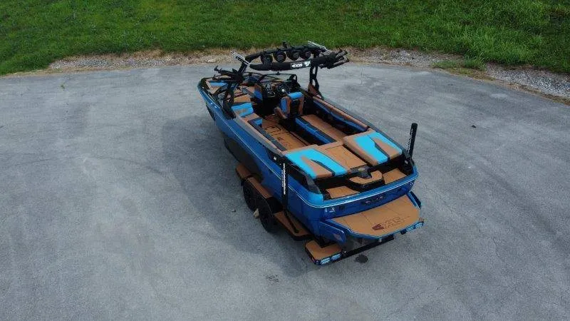 Slide: The Image of A 2027 Axis A245 boat is parked on a lot. It features blue and brown accents. - 10