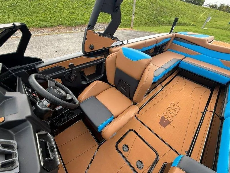 Slide: The Image of The image shows the interior of a 2027 Axis A245 boat with brown and blue seating. - 33