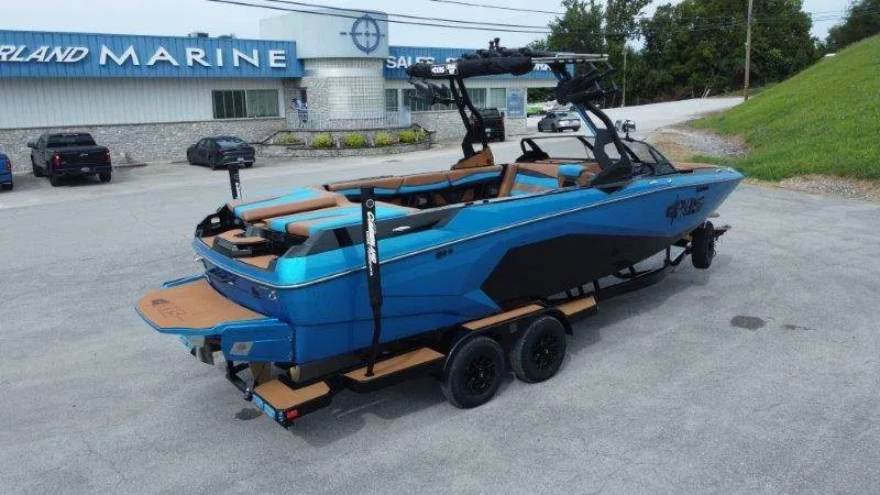 Slide: The Image of A 2027 Axis A245 boat on a trailer in front of a building. It features blue and black paint. - 5