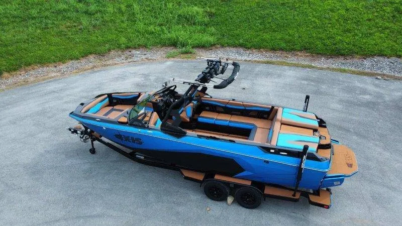 Slide: The Image of A blue and black Axis A245 boat from 2027 sits on a trailer in a paved area. - 9