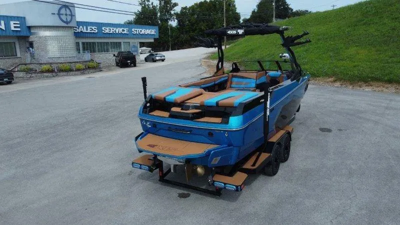 Slide: The Image of A 2027 Axis A245 boat on a trailer in a parking lot. It features blue and brown upholstery. - 11