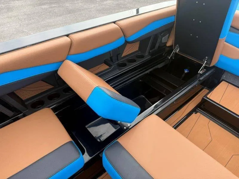 Slide: The Image of The image shows the interior of a 2027 Axis A245 boat with brown and blue seating. - 27