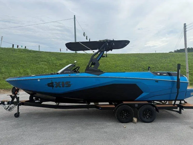Slide: The Image of A blue and black Axis A245 boat from 2027 sits on a trailer in a parking area. - 14
