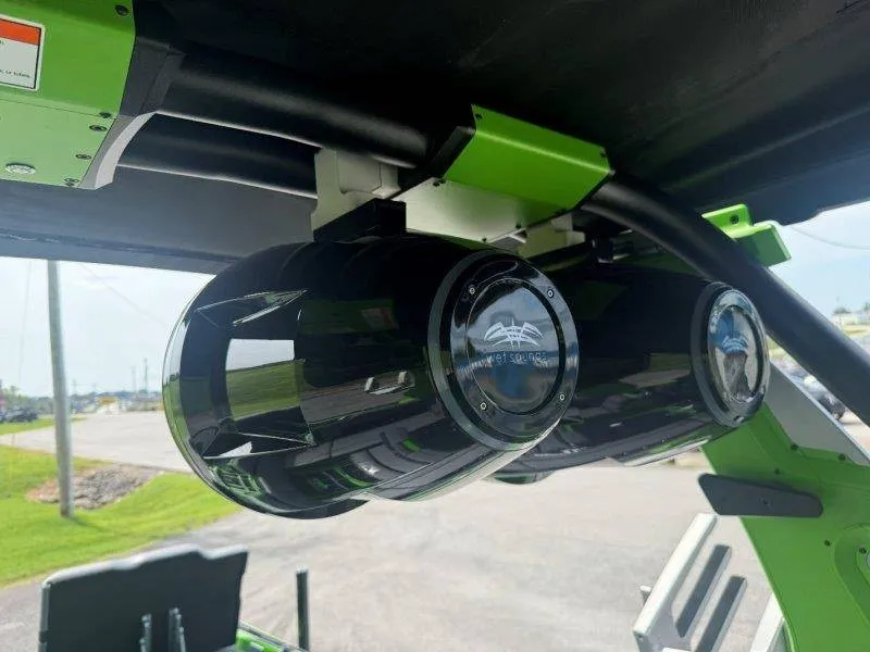 Slide: The Image of Two black speakers are mounted on a green boat, with a clear sky in the background. - 31
