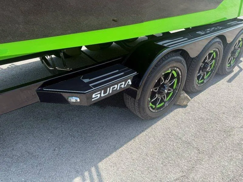 Slide: The Image of A Supra SE 550 boat on a trailer with green accents and black wheels. - 15