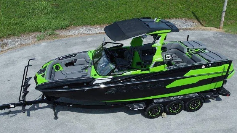 The Image of A 2023 Supra SE 550 boat in black and green on a trailer, featuring a sleek design and spacious interior. - 1