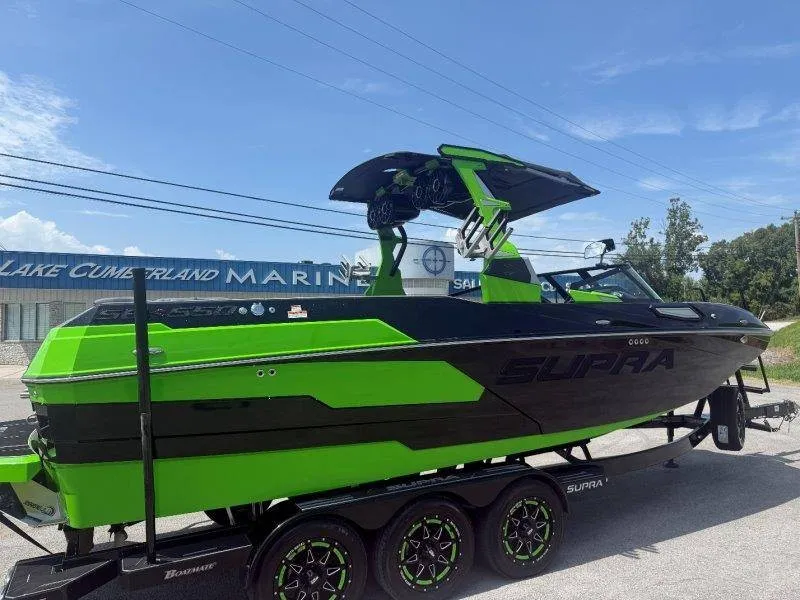 Slide: The Image of A green and black 2023 Supra SE 550 boat on a trailer in front of a building. - 23