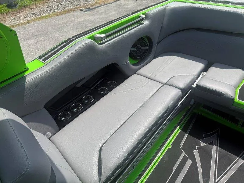 Slide: The Image of The image shows the gray and green seating area of a 2023 Supra SE 550 boat with cup holders. - 37