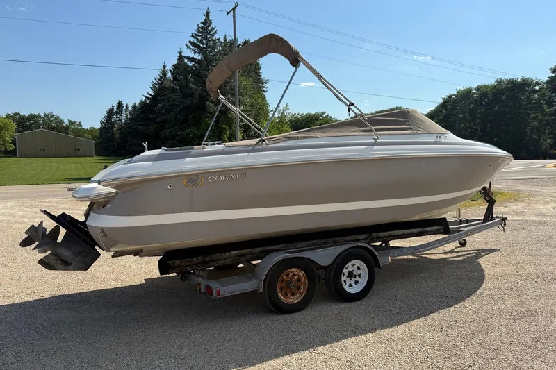 Slide: The Image of 2003 Cobalt 246 boat on trailer, parked outdoors on a sunny day. - 18