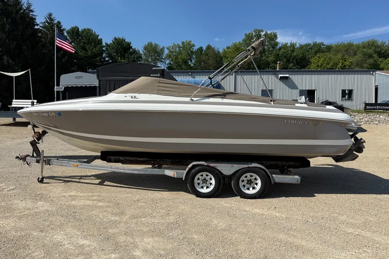 Slide: The Image of 2003 Cobalt 246 boat on trailer, parked outdoors near industrial buildings. - 19