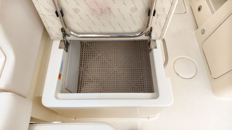 Slide: The Image of An open storage compartment on a 2022 Chris-Craft Calypso 27 boat, featuring a cushioned lid. - 15