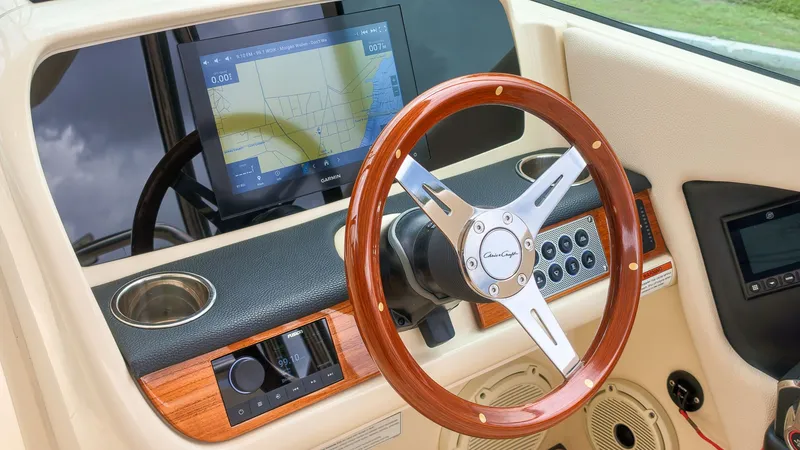 Slide: The Image of The image shows the cockpit of a 2022 Chris-Craft Calypso 27 boat with a sleek wooden steering wheel and modern instruments. - 26
